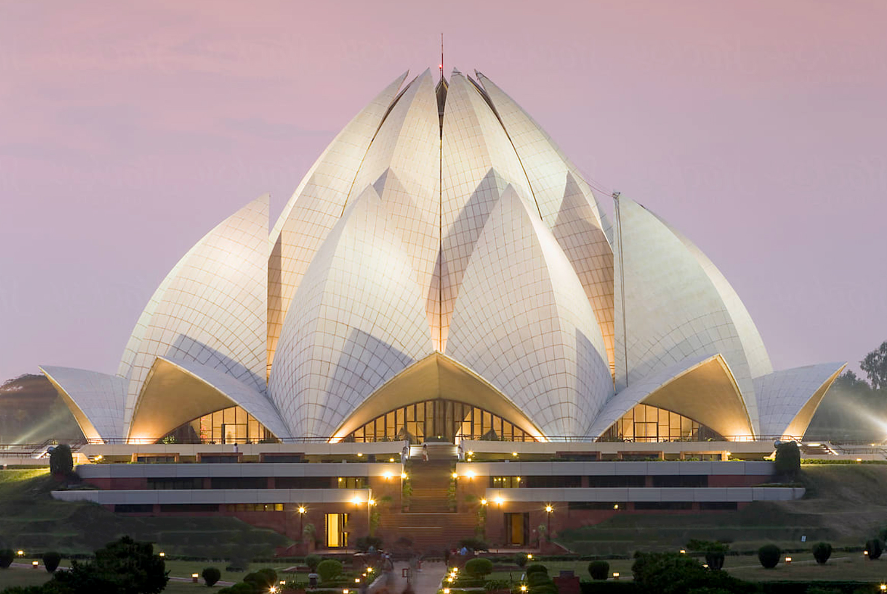 Lotus Temple in New Delhi illuminated at sunset, shaped like a blooming lotus flower