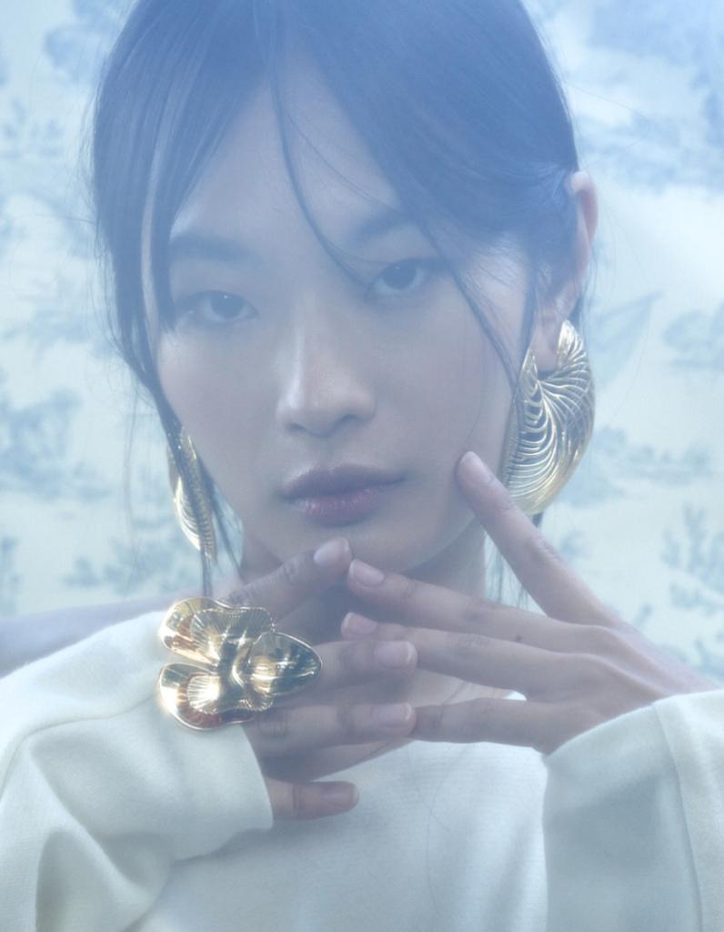 Model wearing a gold contemporary ring and matching contemporary gold earrings by Floa Design as seen in luxury fashion magazine LO'AMMI.
