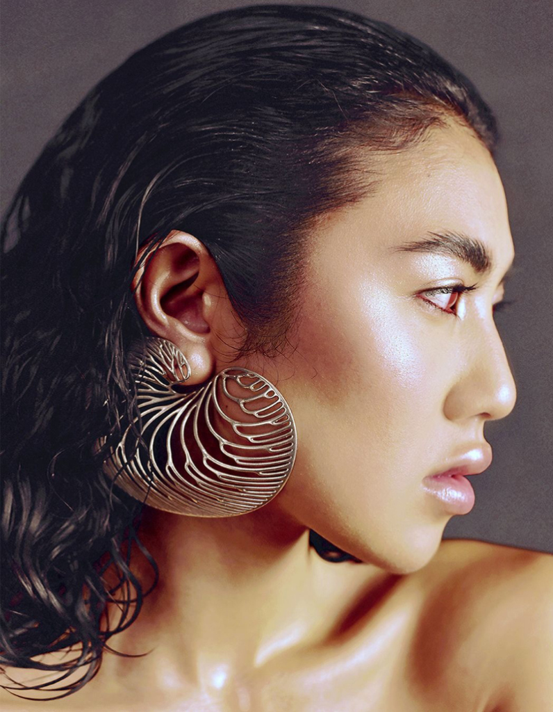 Model wearing bold contemporary silver earrings featuring a flowing sculptural openwork shell design by Floa Design